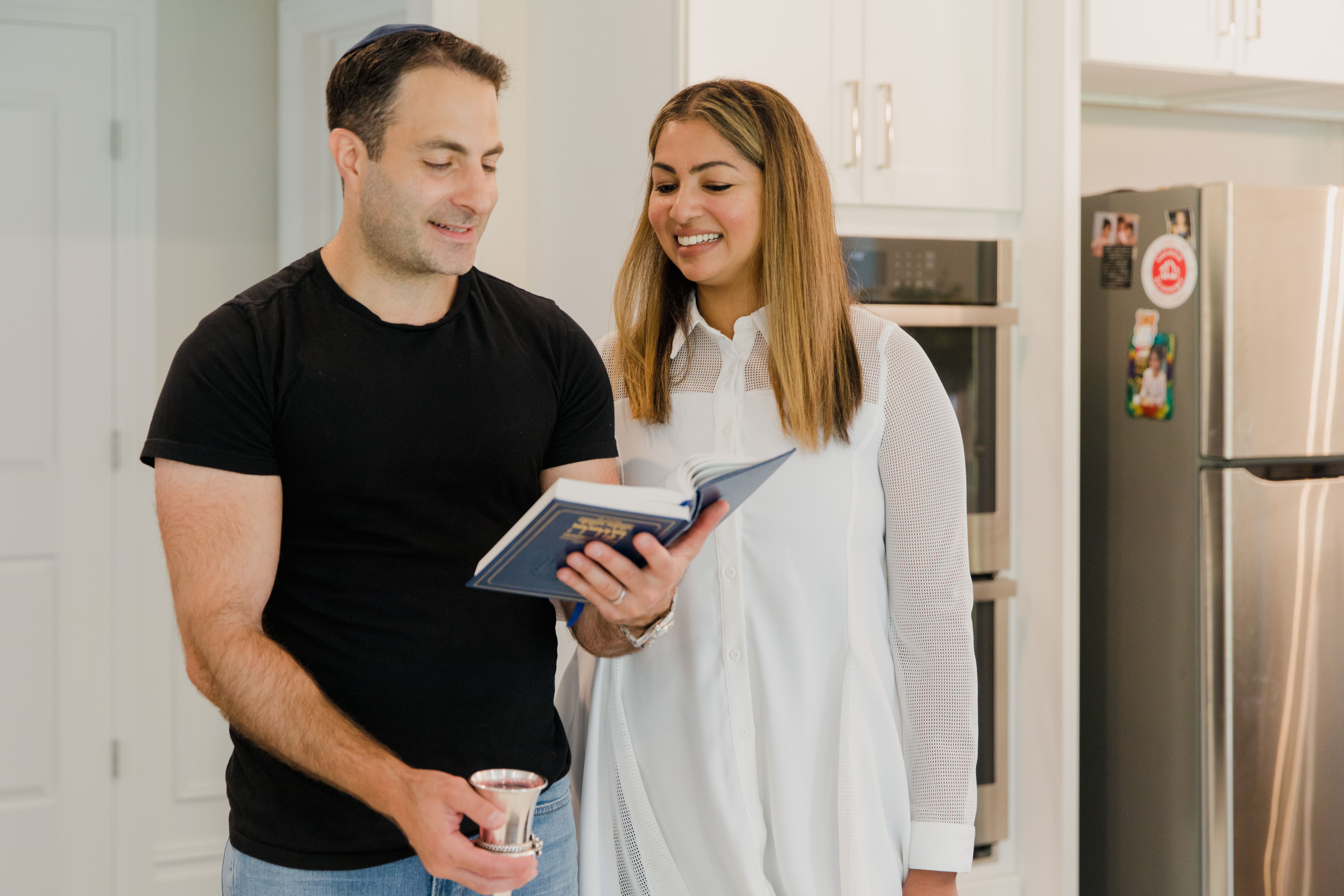 Una pareja sonriente hojea un libro juntos en su cocina
