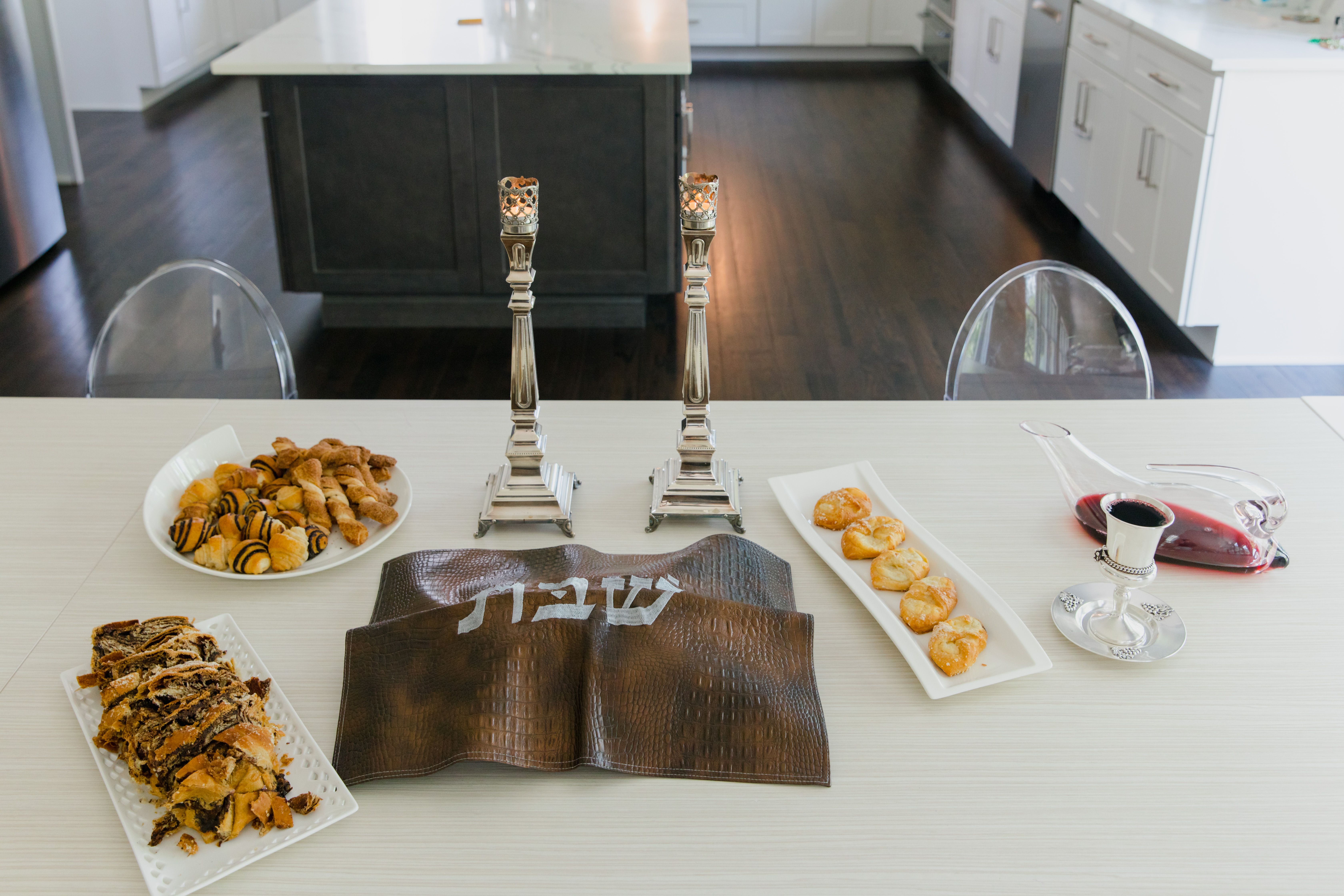 Una mesa de Shabat con candelabros de plata y un cubrejalá bordado